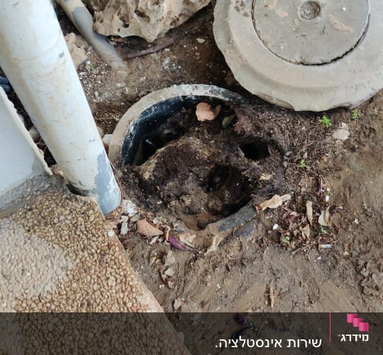 פתח ביוב פתוח עם צינורות ואדמה